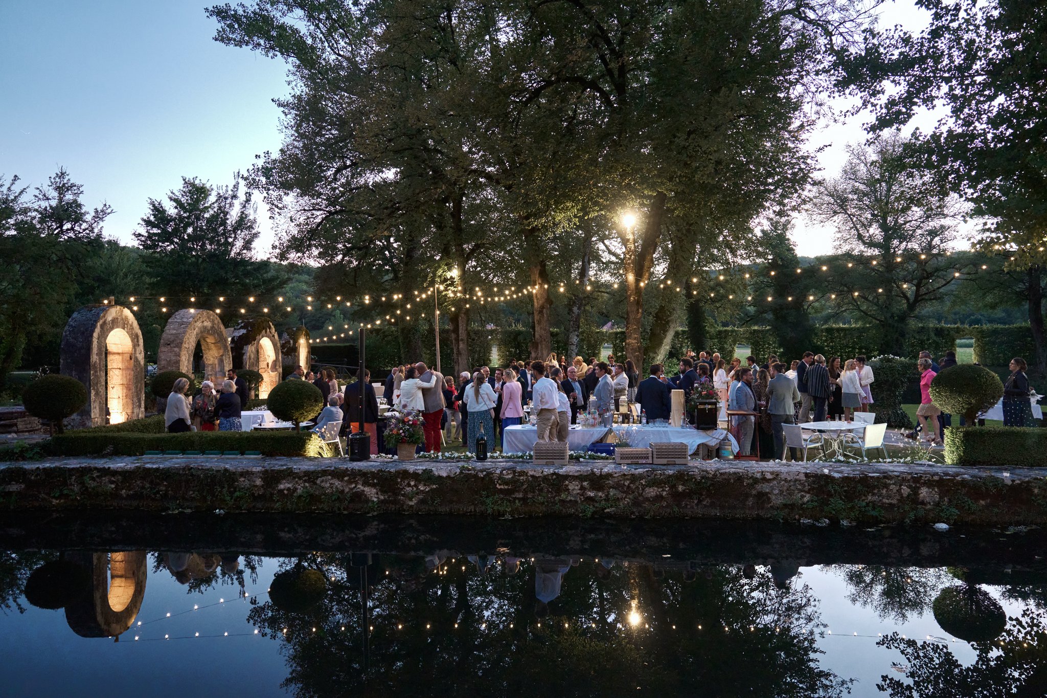 Réception du mariage de Marie-Ève & Aurélien au crépuscule, sous les guirlandes lumineuses.